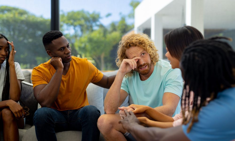 Group of diverse people sitting on sofa and talking in group therapy session. Lifestyle, friendship and support, togetherness, unaltered.